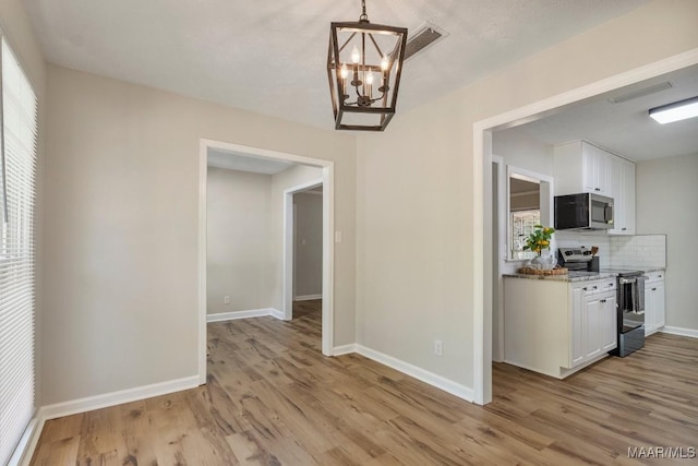 302 Janice St, Prattville, AL 36066 - unfurnished dining area with a chandelier, light wood finished floors, and baseboards