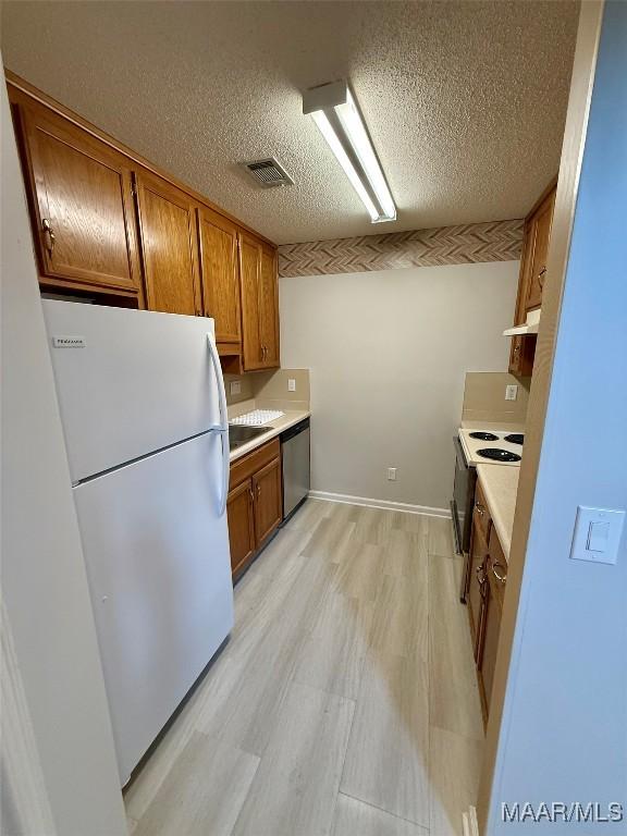 6260 Bell Gables Cir, Montgomery, AL 36117 - kitchen with freestanding refrigerator, stainless steel dishwasher, range with electric stovetop, under cabinet range hood, and brown cabinets