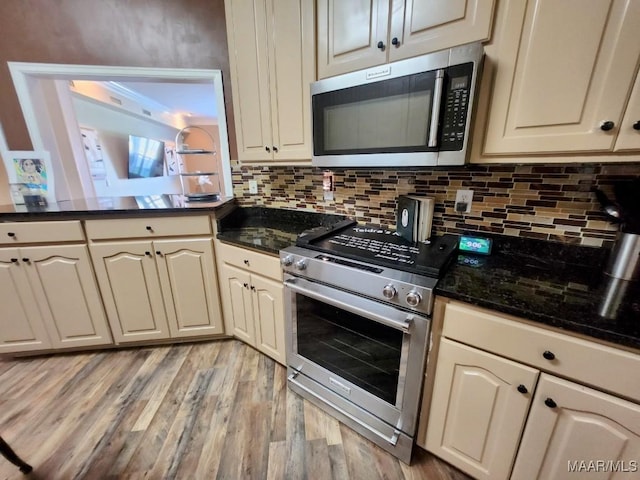 103 River Chase Ct, Wetumpka, AL 36092 - kitchen featuring stainless steel appliances, light wood finished floors, tasteful backsplash, cream cabinets, and dark stone counters