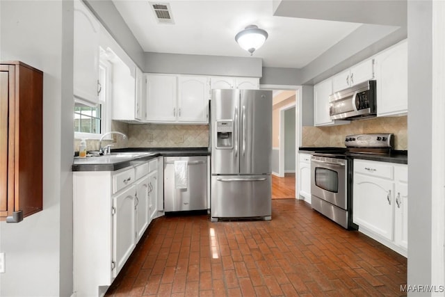 184 Fox Hollow Rd, Montgomery, AL 36109 - kitchen featuring stainless steel appliances, dark countertops, white cabinets, and backsplash