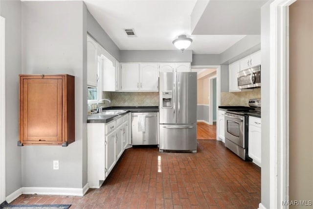 184 Fox Hollow Rd, Montgomery, AL 36109 - kitchen with stainless steel appliances, dark countertops, a sink, decorative backsplash, and white cabinets