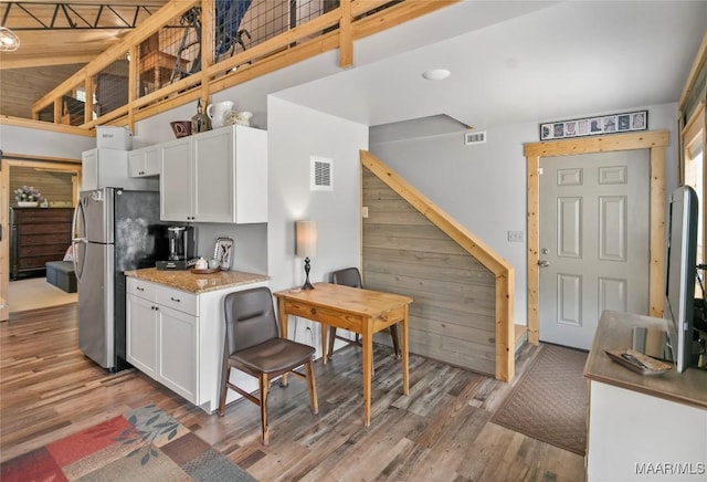 13871 Old Pike Rd, Mathews, AL 36052 - kitchen with wood finished floors, white cabinetry, a towering ceiling, freestanding refrigerator, and light stone countertops