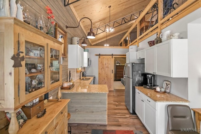 13871 Old Pike Rd, Mathews, AL 36052 - kitchen with a barn door, wooden ceiling, freestanding refrigerator, white cabinetry, and light stone countertops
