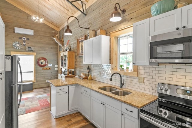 13871 Old Pike Rd, Mathews, AL 36052 - kitchen featuring stainless steel appliances, a sink, wooden walls, decorative backsplash, and a peninsula