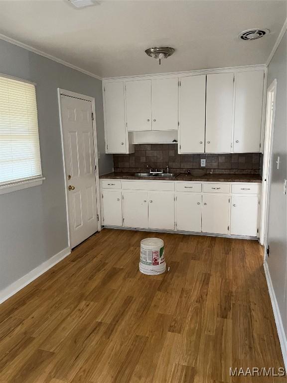 620 6th St, Montgomery, AL 36110 - kitchen with dark countertops, crown molding, decorative backsplash, white cabinets, and baseboards