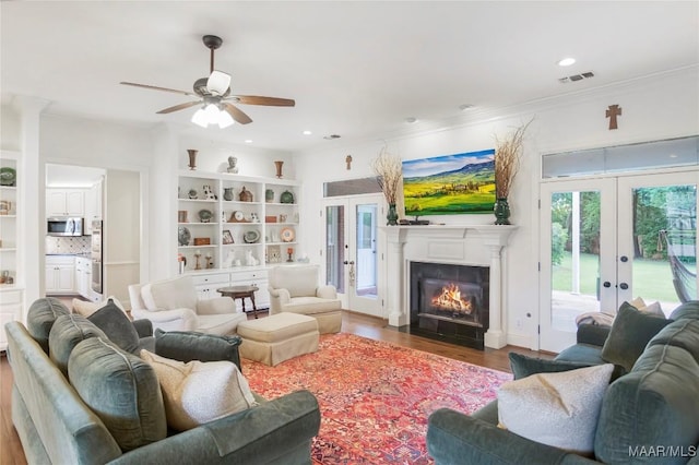 2261 Vaughn Ln, Montgomery, AL 36106 - living area featuring french doors, wood finished floors, ceiling fan, a fireplace with flush hearth, and ornamental molding