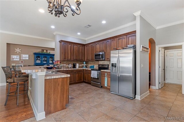 1900 Wyndgate Loop, Montgomery, AL 36117 - kitchen featuring appliances with stainless steel finishes, a peninsula, tasteful backsplash, a sink, and a kitchen breakfast bar