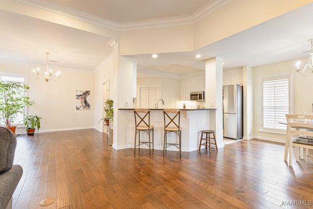 8115 Bridgewater Trce, Montgomery, AL 36117 - kitchen featuring stainless steel appliances, a chandelier, a breakfast bar, dark wood finished floors, and white cabinets