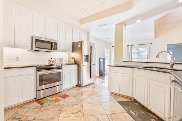 8115 Bridgewater Trce, Montgomery, AL 36117 - kitchen featuring appliances with stainless steel finishes, a sink, decorative backsplash, white cabinetry, and dark countertops