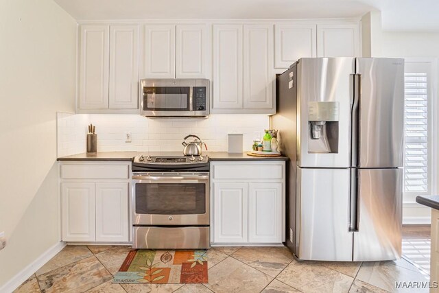 8115 Bridgewater Trce, Montgomery, AL 36117 - kitchen featuring stainless steel appliances, decorative backsplash, white cabinets, dark countertops, and baseboards