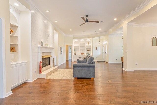 8115 Bridgewater Trce, Montgomery, AL 36117 - living room with built in features, ceiling fan, hardwood / wood-style floors, a tile fireplace, and ornamental molding