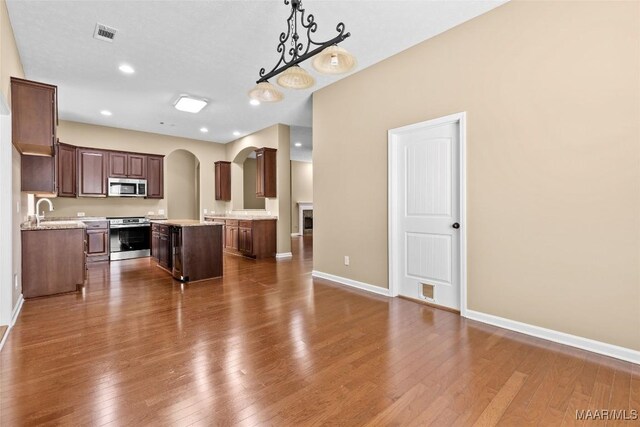 9000 Finsburry Ct, Montgomery, AL 36117 - kitchen featuring stainless steel appliances, a center island, arched walkways, dark wood finished floors, and light countertops