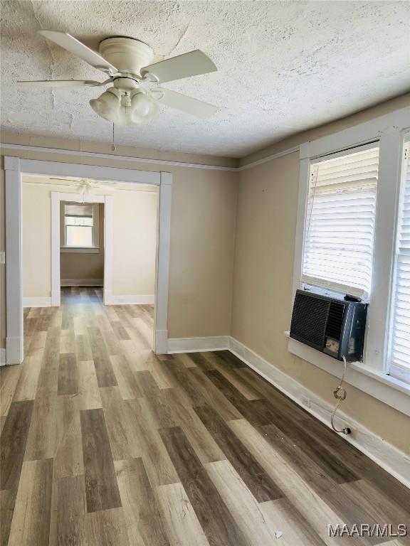 2829 Highland Ave, Montgomery, AL 36107 - spare room featuring wood finished floors, a textured ceiling, baseboards, a ceiling fan, and cooling unit