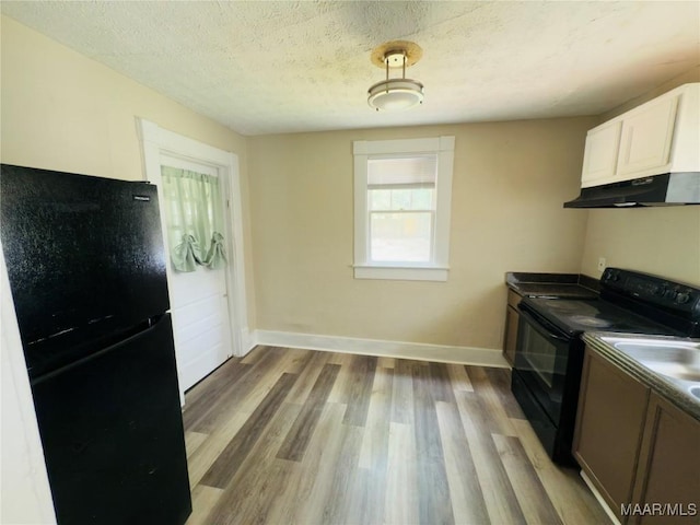 2829 Highland Ave, Montgomery, AL 36107 - kitchen with black appliances, under cabinet range hood, light wood finished floors, baseboards, and white cabinets