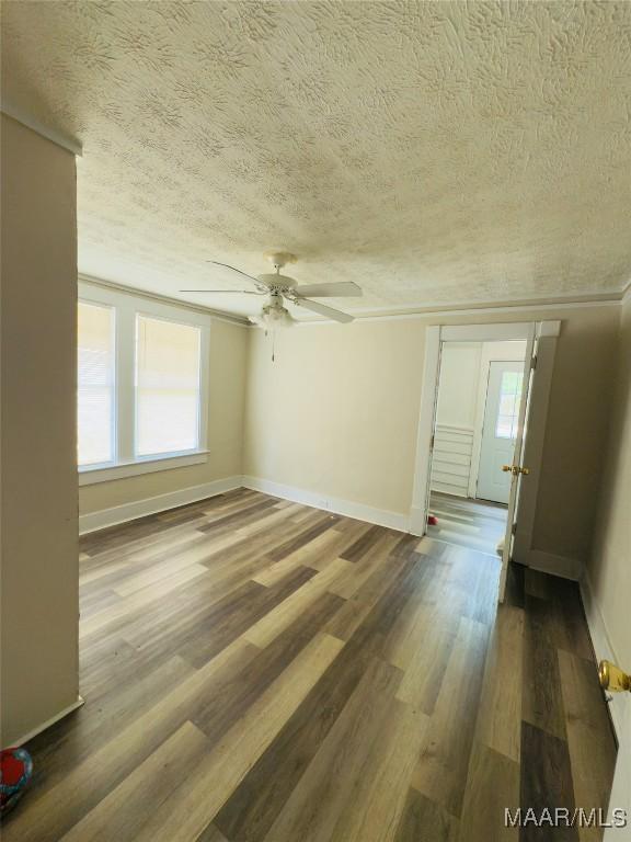 2829 Highland Ave, Montgomery, AL 36107 - unfurnished room featuring a textured ceiling, a ceiling fan, plenty of natural light, wood finished floors, and baseboards