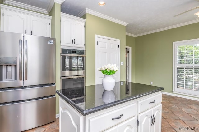 3049 Fieldcrest Dr, Montgomery, AL 36106 - kitchen with stainless steel appliances, white cabinetry, dark stone counters, ornamental molding, and light tile patterned flooring