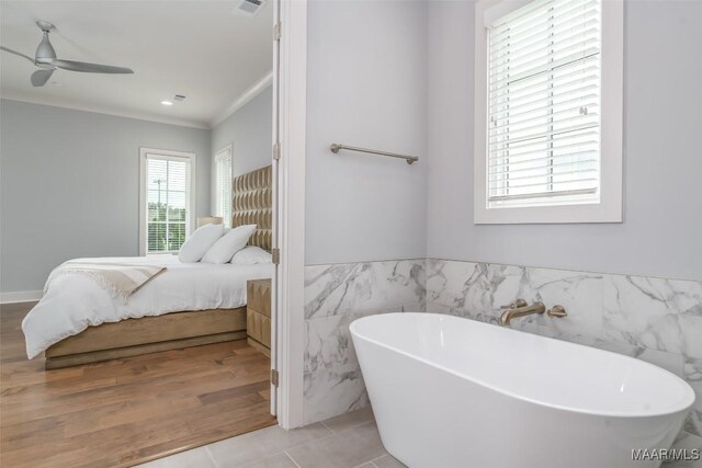7175 Fain Park Loop, Montgomery, AL 36117 - ensuite bathroom with tile walls, a freestanding tub, ceiling fan, wainscoting, and crown molding