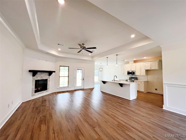 40 Serene Ln, Wetumpka, AL 36093 - unfurnished living room with a tray ceiling, wood finished floors, ceiling fan, recessed lighting, and a lit fireplace