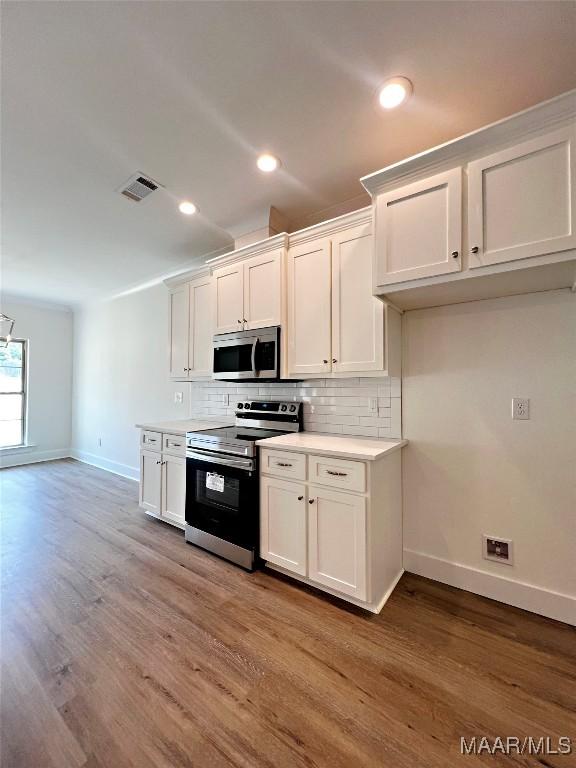 40 Serene Ln, Wetumpka, AL 36093 - kitchen featuring appliances with stainless steel finishes, decorative backsplash, wood finished floors, white cabinetry, and recessed lighting