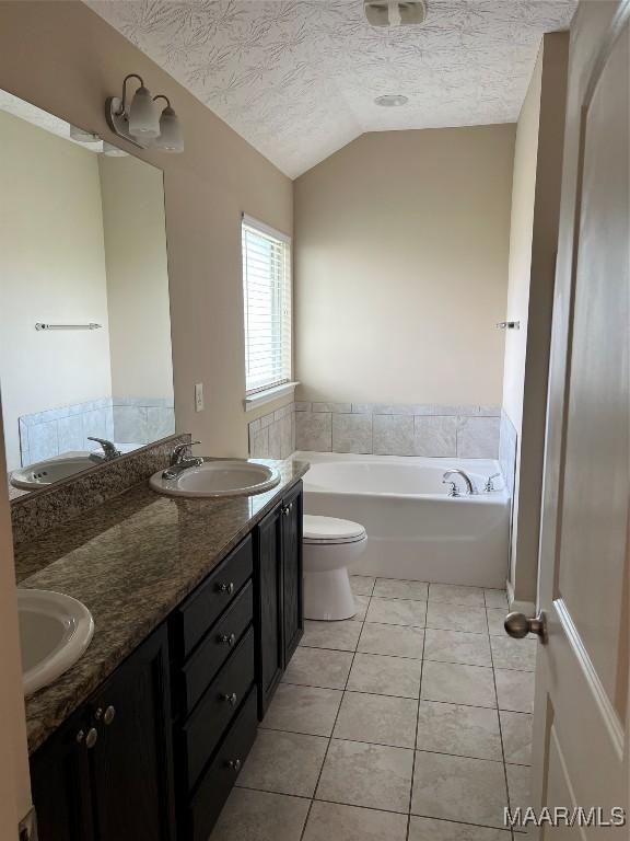 19 High Cotton Ct, Wetumpka, AL 36092 - full bathroom featuring lofted ceiling, a garden tub, double vanity, toilet, and tile patterned flooring
