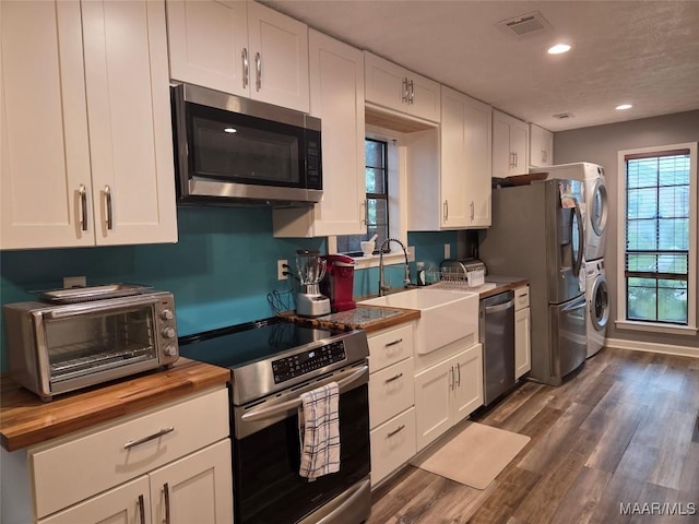 2112 Station Ct, Montgomery, AL 36116 - kitchen with stainless steel appliances, estacked washer and dryer, wooden counters, a sink, and white cabinets