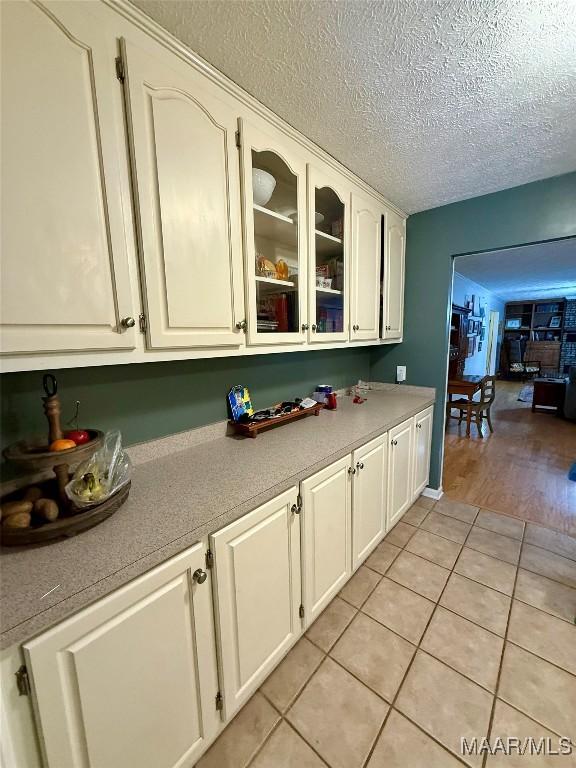 530 Palmquist Dr, Selma, AL 36701 - kitchen featuring light tile patterned flooring, glass insert cabinets, light countertops, white cabinets, and a textured ceiling