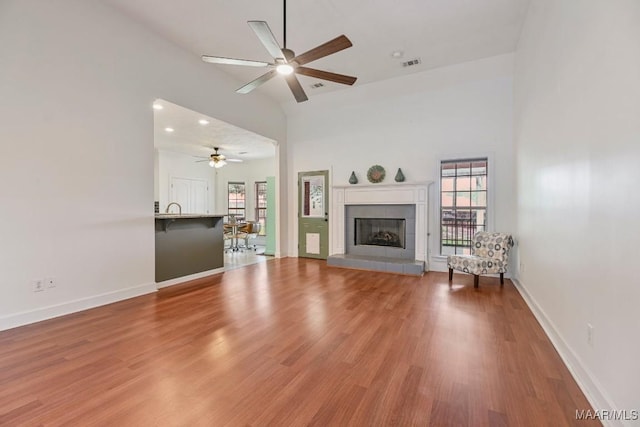 505 Mountain Ridge Rd, Millbrook, AL 36054 - unfurnished living room featuring a ceiling fan, plenty of natural light, wood finished floors, a tiled fireplace, and a towering ceiling