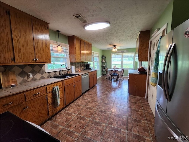 445 W Hickory Grove Rd, Lapine, AL 36046 - kitchen featuring appliances with stainless steel finishes, a sink, tile counters, brown cabinetry, and brick patterned flooring