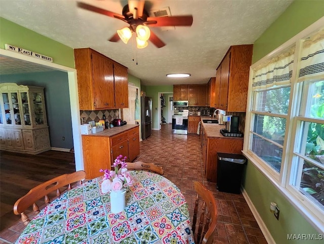 445 W Hickory Grove Rd, Lapine, AL 36046 - kitchen with stainless steel appliances, brown cabinets, tasteful backsplash, baseboards, and a textured ceiling