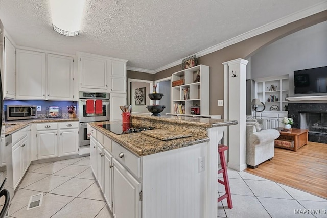 594 Lewis Rd, Deatsville, AL 36022 - kitchen with appliances with stainless steel finishes, light tile patterned floors, a center island, white cabinetry, and light stone counters