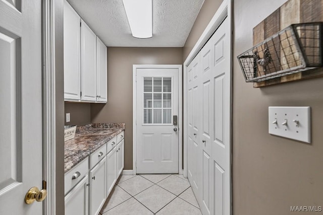 594 Lewis Rd, Deatsville, AL 36022 - laundry area featuring light tile patterned floors, a textured ceiling, and baseboards