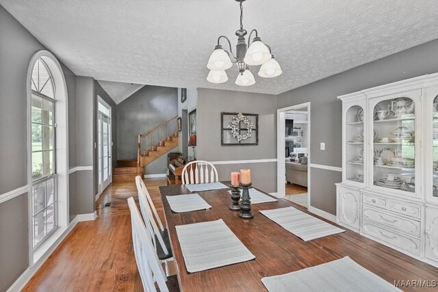 594 Lewis Rd, Deatsville, AL 36022 - dining area with a chandelier, stairway, a textured ceiling, wood finished floors, and baseboards