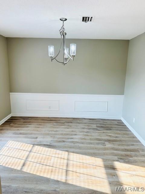 6118 Helga Pl, Montgomery, AL 36117 - unfurnished dining area featuring a chandelier, wood finished floors, a wainscoted wall, and baseboards