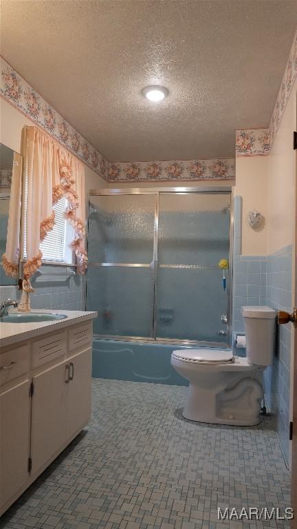 22 Daleview Cir, Sylacauga, AL 35150 - bathroom featuring toilet, tile walls, a textured ceiling, vanity, and enclosed tub / shower combo