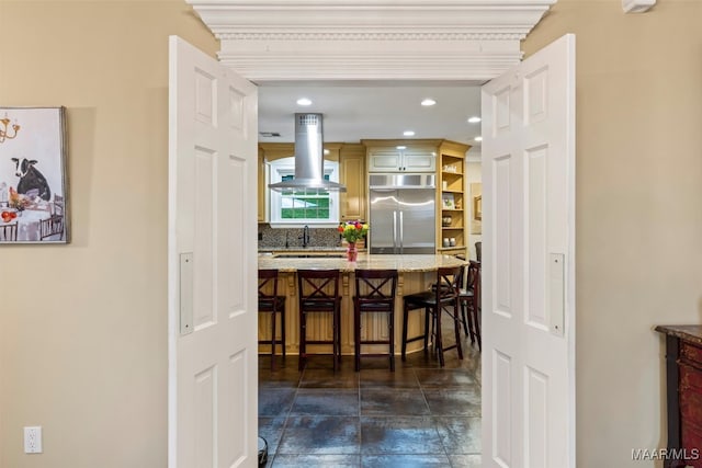 161 Watson Cir, Montgomery, AL 36109 - kitchen with stainless steel built in refrigerator, island exhaust hood, backsplash, a kitchen bar, and light stone countertops