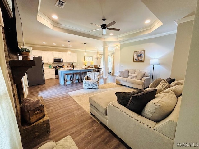1670 Rifle Range Rd, Wetumpka, AL 36093 - living room with decorative columns, ornamental molding, a tray ceiling, a ceiling fan, and wood finished floors