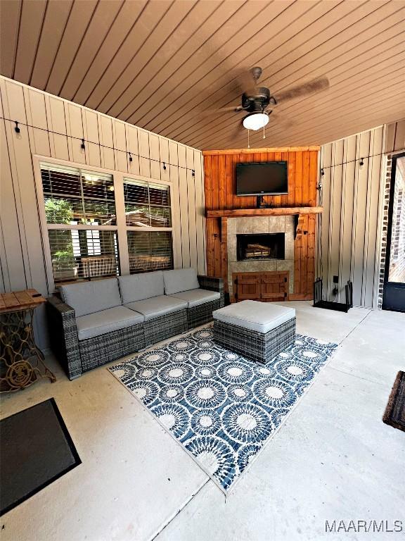 475 Mountain Meadows Ln, Wetumpka, AL 36093 - living room featuring wooden walls, concrete floors, a ceiling fan, and an outdoor fireplace