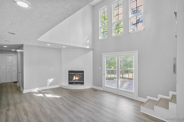 21 Judge Ests, Hope Hull, AL 36043 - unfurnished living room featuring wood finished floors, a towering ceiling, baseboards, a tile fireplace, and recessed lighting