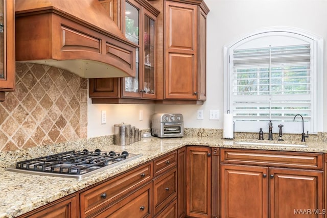 3900 Turning Leaf Loop, Montgomery, AL 36116 - kitchen featuring a sink, stainless steel gas cooktop, custom exhaust hood, light stone countertops, and glass insert cabinets