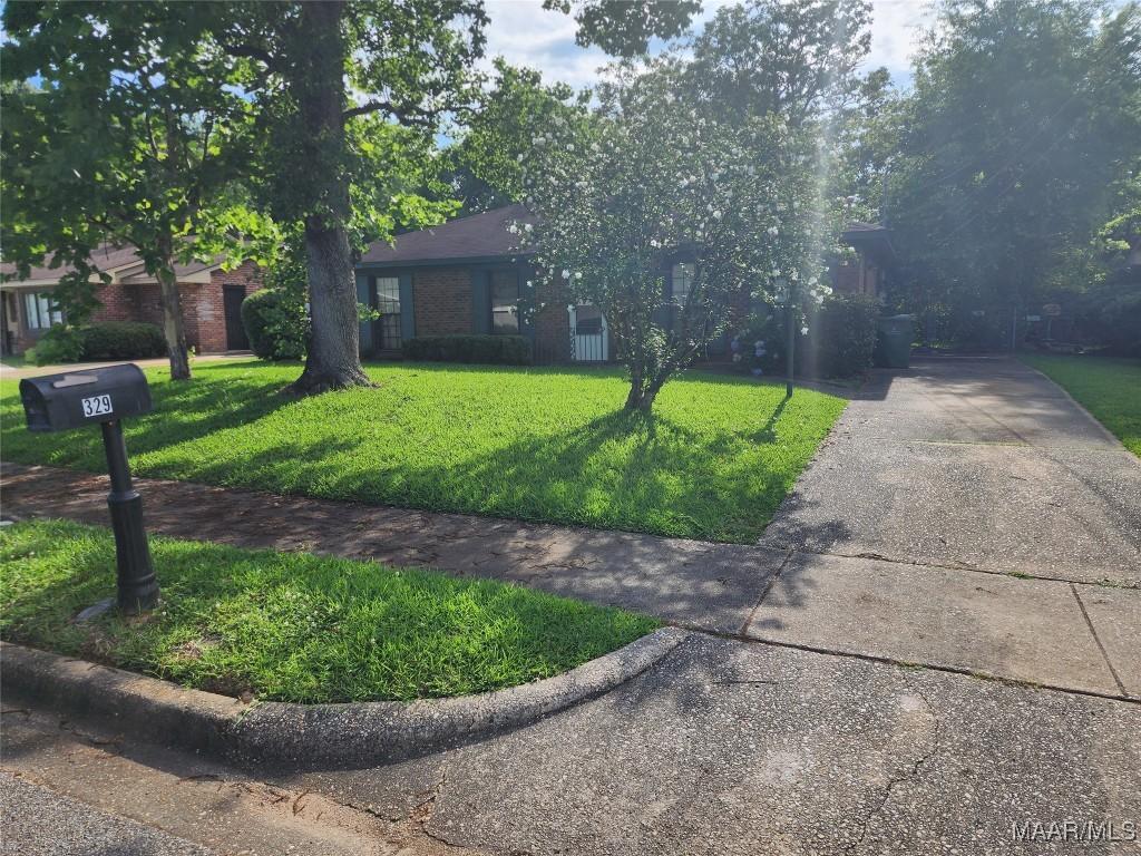 329 Sultan Ct, Montgomery, AL 36117 - view of property hidden behind natural elements with concrete driveway, a front lawn, and brick siding