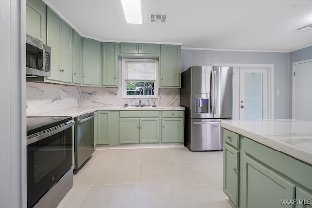5736 Roxboro Dr, Montgomery, AL 36117 - kitchen featuring green cabinets, appliances with stainless steel finishes, decorative backsplash, light tile patterned floors, and crown molding
