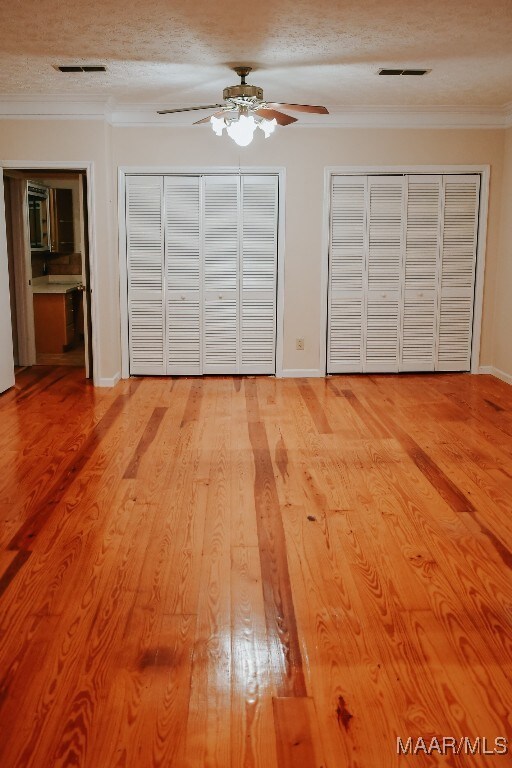 813 Lake Region Cir, Wetumpka, AL 36092 - unfurnished bedroom featuring two closets, crown molding, a textured ceiling, light wood-style flooring, and ceiling fan