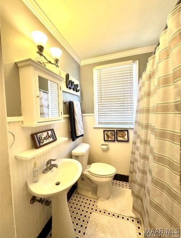1915 Mckinley Ave, Montgomery, AL 36107 - bathroom featuring toilet, wainscoting, ornamental molding, tile patterned floors, and a shower with curtain