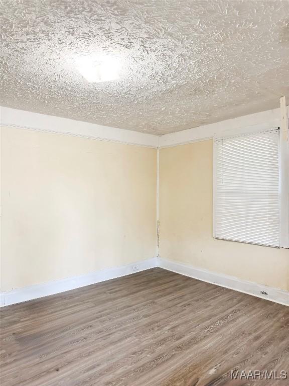 1422 S Holt St, Montgomery, AL 36108 - unfurnished room with wood finished floors, baseboards, and a textured ceiling