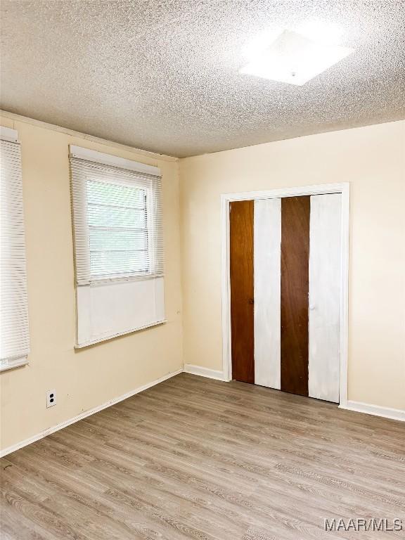 1422 S Holt St, Montgomery, AL 36108 - unfurnished bedroom featuring a textured ceiling, light wood-type flooring, a closet, and baseboards
