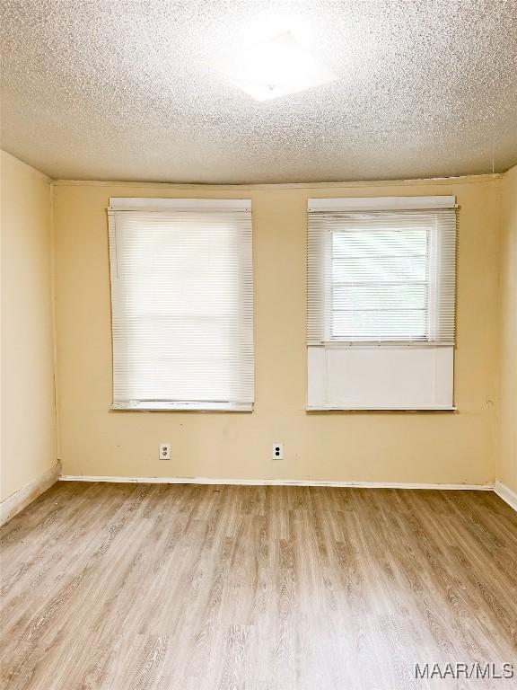 1422 S Holt St, Montgomery, AL 36108 - empty room with wood finished floors, a textured ceiling, and baseboards