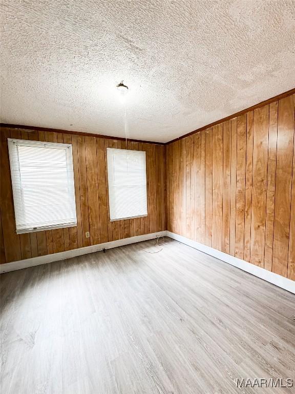 1422 S Holt St, Montgomery, AL 36108 - unfurnished room featuring wood finished floors, a textured ceiling, wooden walls, and baseboards