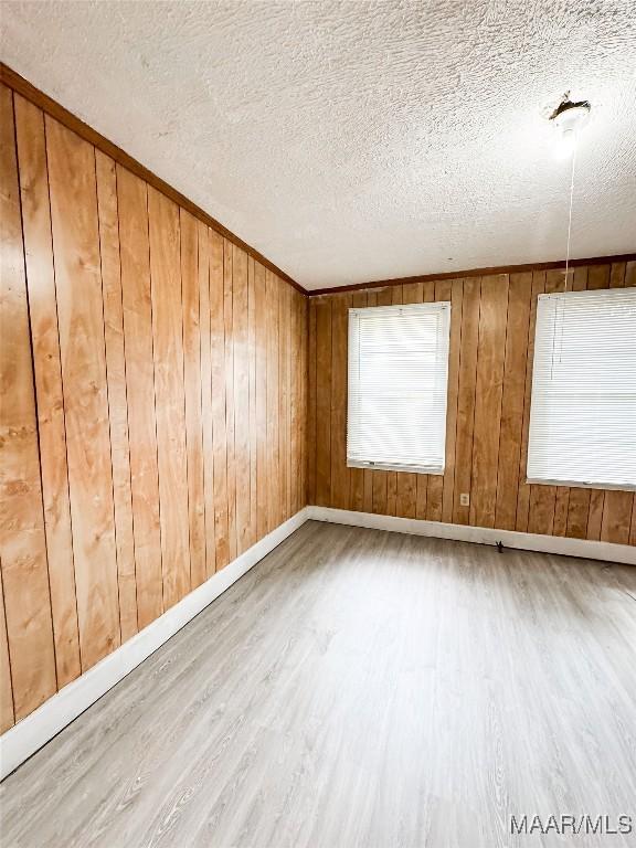 1422 S Holt St, Montgomery, AL 36108 - spare room featuring wood finished floors, a textured ceiling, baseboards, and wooden walls