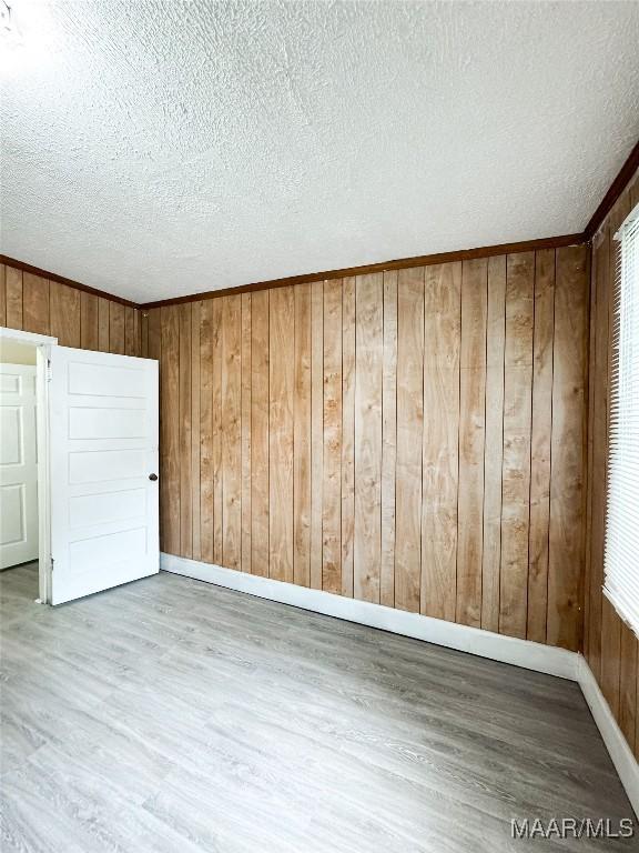1422 S Holt St, Montgomery, AL 36108 - unfurnished room with wood finished floors, a textured ceiling, baseboards, and wood walls