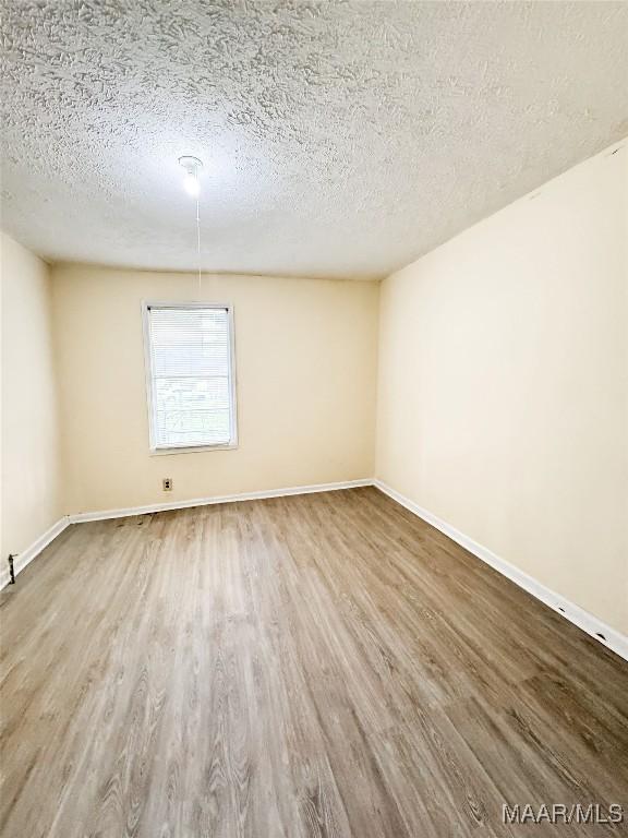 1422 S Holt St, Montgomery, AL 36108 - unfurnished room with wood finished floors, a textured ceiling, and baseboards